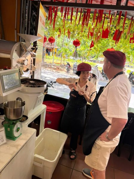Guest learning about coffee roasting beside the roaster at Tri Long Coffee Roastery
