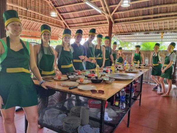 Visitors preparing traditional Vietnamese dishes together during a cooking class in Hoi An