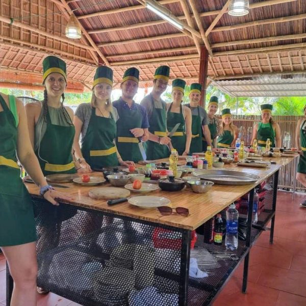 Visitors preparing traditional Vietnamese dishes together during a cooking class in Hoi An