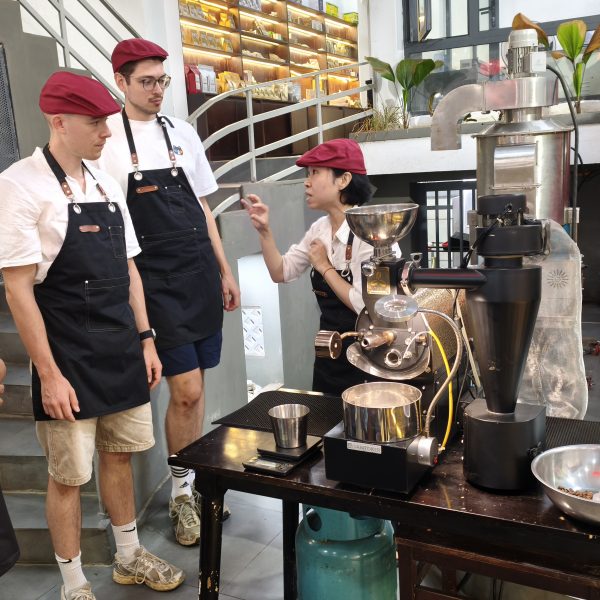 Guests learning about coffee roaster operation and roast settings for light, medium, and dark roasts in Hoi An