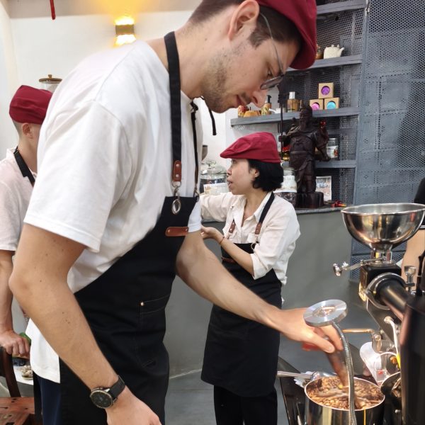 Guests cooling freshly roasted coffee beans during a coffee roasting experience in Hoi An