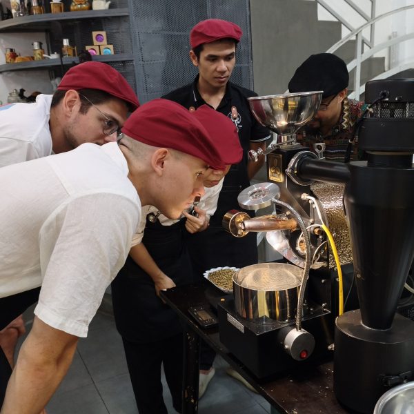 Guests monitoring temperature and bean color after first crack during a coffee roasting experience in Hoi An