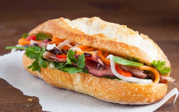 Vietnamese banh mi sandwich with crispy baguette, pate, meat, pickled vegetables and fresh cilantro