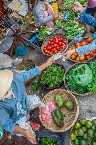 Visitors exploring a traditional market with local vendors and fresh produce in Hoi An, Vietnam.