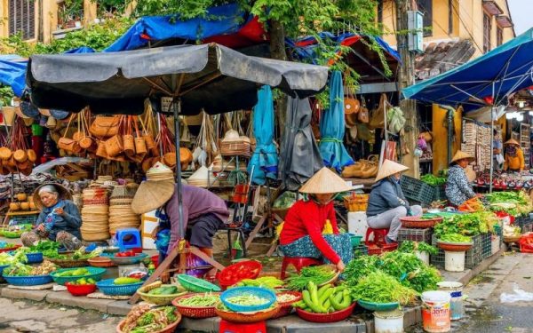 Local vendors selling fresh vegetables and herbs at a traditional morning market in Hoi An, Vietnam.