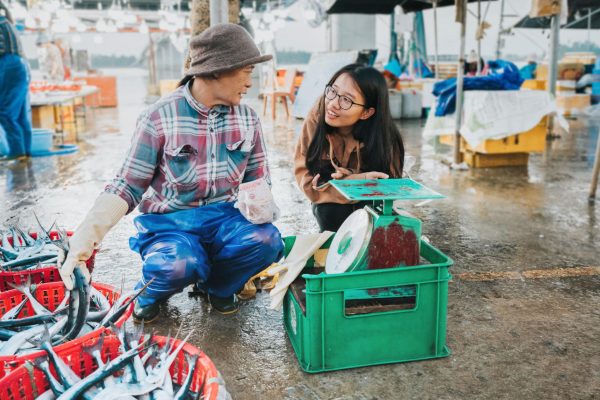 A Vietnamese market vendor chatting with a customer at a traditional market in Hoi An.